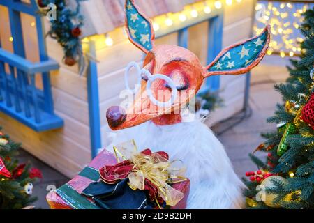 Eine Statue eines Fuchses mit einem Geschenk in der Nähe des Weihnachtsbaums, Dekoration für das neue Jahr. Weihnachtskomposition in Moskau auf dem Maneschnaja-Platz - Moskau, Rus Stockfoto