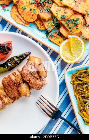 Gegrilltes Fleisch, Meeresfrüchte, Meze, Kräuter, Fisch, Raki, Ouzo, Vorspeisen und Salate im griechischen oder türkischen Restaurant auf dem Tisch zum Abendessen oder Mittagessen am Strand Stockfoto