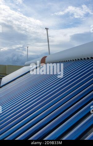 Sonnenkollektoren und Rohre auf Hausdächern installiert und Gebäudetüken, um Energie für die Warmwasserbereitung zu sparen Stockfoto