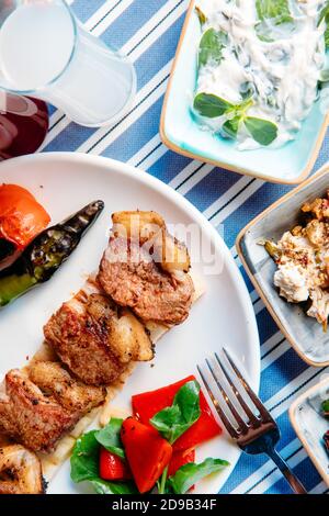 Gegrilltes Fleisch, Meeresfrüchte, Meze, Kräuter, Fisch, Raki, Ouzo, Vorspeisen und Salate im griechischen oder türkischen Restaurant auf dem Tisch zum Abendessen oder Mittagessen am Strand Stockfoto