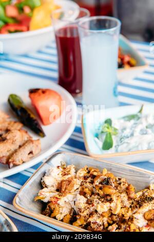 Gegrilltes Fleisch, Meeresfrüchte, Meze, Kräuter, Fisch, Raki, Ouzo, Vorspeisen und Salate im griechischen oder türkischen Restaurant auf dem Tisch zum Abendessen oder Mittagessen am Strand Stockfoto