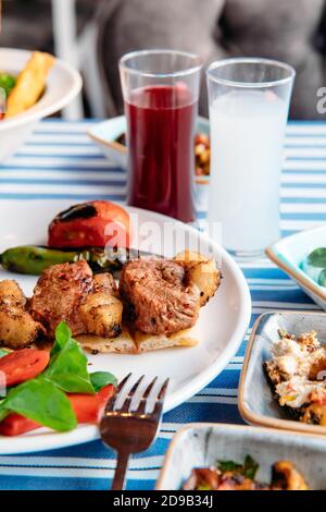 Gegrilltes Fleisch, Meeresfrüchte, Meze, Kräuter, Fisch, Raki, Ouzo, Vorspeisen und Salate im griechischen oder türkischen Restaurant auf dem Tisch zum Abendessen oder Mittagessen am Strand Stockfoto