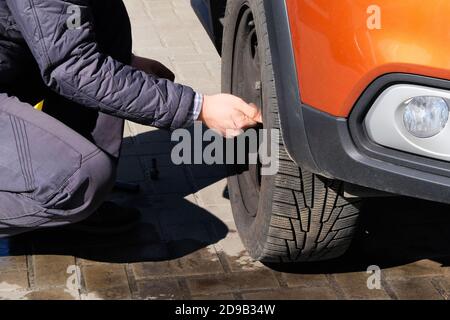 Entfernen des Gummis von der Radscheibe. Autoservice. Reifenwechsel auf der Straße. Auto-Reparatur-Konzept. Stockfoto