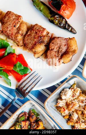 Gegrilltes Fleisch, Meeresfrüchte, Meze, Kräuter, Fisch, Raki, Ouzo, Vorspeisen und Salate im griechischen oder türkischen Restaurant auf dem Tisch zum Abendessen oder Mittagessen am Strand Stockfoto