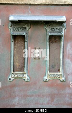 Gedeckter Briefmarkenautomat im Postamt in der Maybole High Street, Ayrshire, Schottland. Auf dem Schild steht: „ Warten Sie auf die Lieferung des Stempels, bevor Sie eine weitere Münze einlegen“. Stockfoto