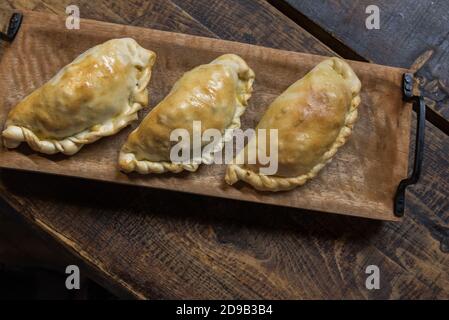 Traditionelle gebackene argentinische und Uruguay Empanadas herzhaftes Gebäck mit Fleischbeef Füllung vor Holzhintergrund. Stockfoto