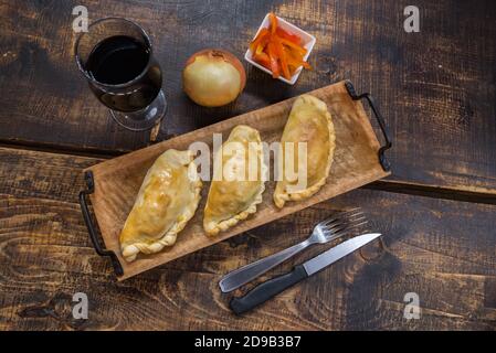 Traditionelle gebackene argentinische und Uruguay Empanadas herzhaftes Gebäck mit Fleischbeef Füllung vor Holzhintergrund. Stockfoto