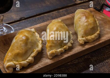 Traditionelle gebackene argentinische und Uruguay Empanadas herzhaftes Gebäck mit Fleischbeef Füllung vor Holzhintergrund. Stockfoto