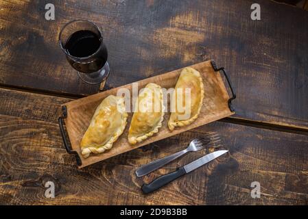 Traditionelle gebackene argentinische und Uruguay Empanadas herzhaftes Gebäck mit Fleischbeef Füllung vor Holzhintergrund. Stockfoto