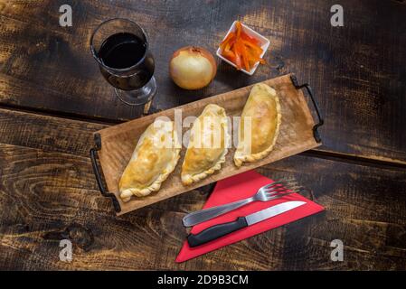 Traditionelle gebackene argentinische und Uruguay Empanadas herzhaftes Gebäck mit Fleischbeef Füllung vor Holzhintergrund. Stockfoto