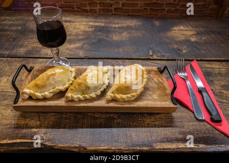 Traditionelle gebackene argentinische und Uruguay Empanadas herzhaftes Gebäck mit Fleischbeef Füllung vor Holzhintergrund. Stockfoto