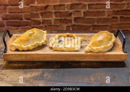 Traditionelle gebackene argentinische und Uruguay Empanadas herzhaftes Gebäck mit Fleischbeef Füllung vor Holzhintergrund. Stockfoto