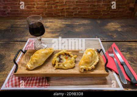 Traditionelle gebackene argentinische und Uruguay Empanadas herzhaftes Gebäck mit Fleischbeef Füllung vor Holzhintergrund. Stockfoto