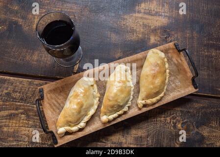 Traditionelle gebackene argentinische und Uruguay Empanadas herzhaftes Gebäck mit Fleischbeef Füllung vor Holzhintergrund. Stockfoto