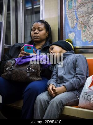 NEW YORK, USA - 30. Apr 2016: Schwarze Frau mit Kind und Handy in New York City U-Bahn. NYC Subway ist eine der ältesten und umfangreichsten öffentlichen Stockfoto