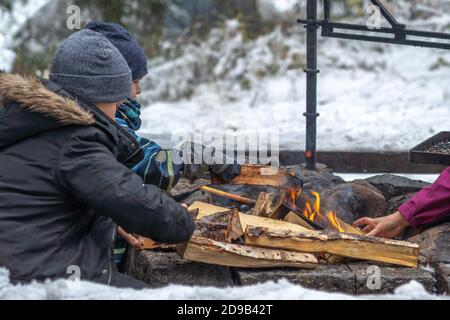 Asikkala, Finnland Finnland 21. Oktober 2020 Herbst. Erster Schnee, Touristen im Freien in der Natur. Wärmt seine Hände durch das Feuer. Reise- und Reisekonzept. Hochwertige Fotos Stockfoto