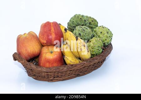 Frische Äpfel, Bananen und Puddingäpfel auf einem Holzkorb Stockfoto