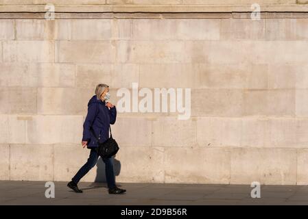 Westminster, London, Großbritannien. November 2020. London hat einen hellen, aber kühlen Tag genossen, an dem die Menschen die Gelegenheit nutzen, es vor der COVID-19-Sperre zu besuchen. Frau trägt Gesichtsmaske vorbei an der National Gallery Stockfoto