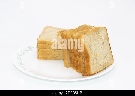 Scheiben frisch gebackenes Brot auf Teller mit Weiß gehalten Hintergrund Stockfoto