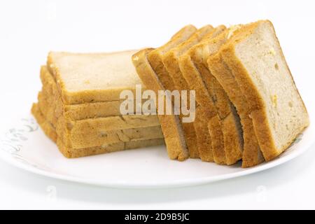 Scheiben frisch gebackenes Brot auf Teller mit Weiß gehalten Hintergrund Stockfoto