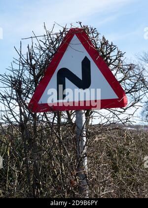 Ein doppeltes Biegezeichen verschmilzt langsam mit einer Hecke Stockfoto