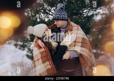 Eine junge Frau und ein Mann umarmen sich unter einem gemütlichen Karierte Decke Stockfoto