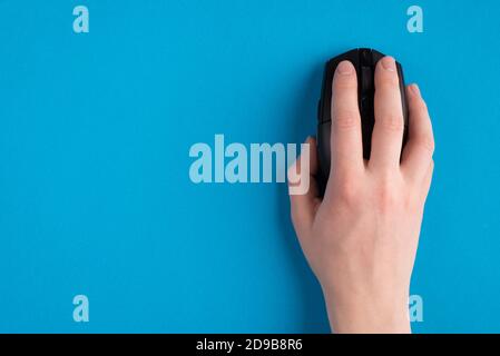 Oben über der Decke Nahaufnahme der ersten Person Foto von Menschliche weibliche Hand hält Laptop Computer drahtlose schwarze Maus isoliert Über heller Farbe blau Stockfoto