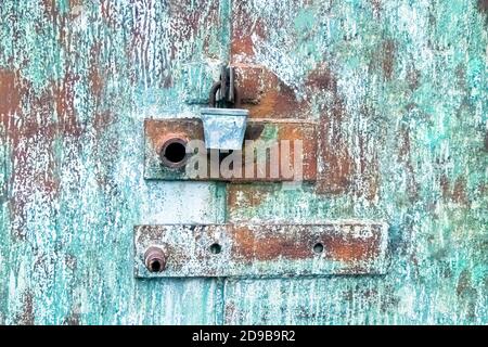 Metallstruktur mit altem Schloss in braun und blau. Silbernes Vorhängeschloss an der alten blauen Tür. Stockfoto