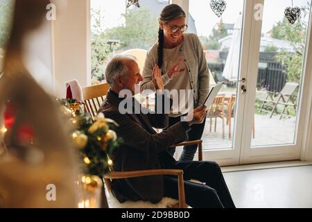 Ältere Paare, die an Weihnachten ein digitales Tablet für Videoanrufe bei ihrer Familie verwenden. Ältere Männer und Frauen, die einen Videoanruf führen. Stockfoto