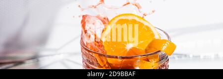 Orangenschale im Glas mit spritzerem Alkoholcocktail auf weißem Banner Stockfoto