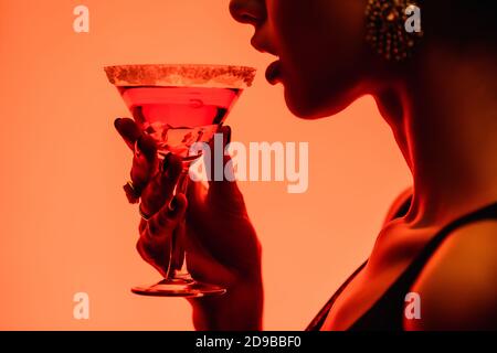 Beschnittene Ansicht der Frau trinken margarita Cocktail auf orange Stockfoto