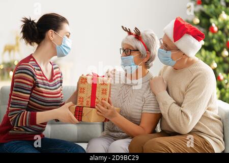 Menschen mit Geschenken tragen Gesichtsmasken während Coronavirus und Grippe Ausbruch an Weihnachten. Schutz vor Viren und Krankheiten, Quarantäne zu Hause. COVID-2019 Stockfoto