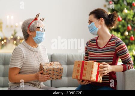 Menschen mit Geschenken tragen Gesichtsmasken während Coronavirus und Grippe Ausbruch an Weihnachten. Schutz vor Viren und Krankheiten, Quarantäne zu Hause. COVID-2019 Stockfoto