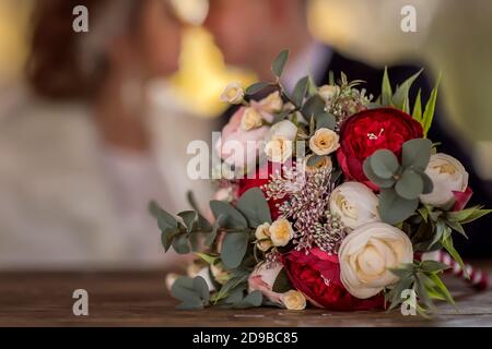 Brautstrauß der Braut bestehend aus roten Rosen, beigen Rosen und Eukalyptusblättern. Blumenstrauß aus nächster Nähe. Stockfoto