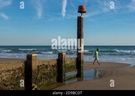 Eine Einzelperson geht bei Ebbe am Boscombe Beach, Bournemouth, Dorset am Ufer des Wassers entlang. 29. September 2015. Foto: Neil Turner Stockfoto