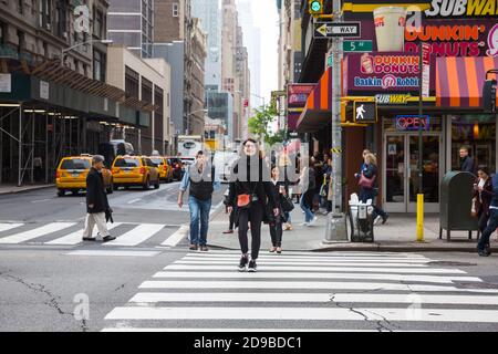 NEW YORK, USA - 02. Mai 2016: Kreuzung von 5th Av und W 31 St in NYC. Junge charmante Mädchen überquert die Straße an einem Fußgängerübergang. Manhattan stree Stockfoto