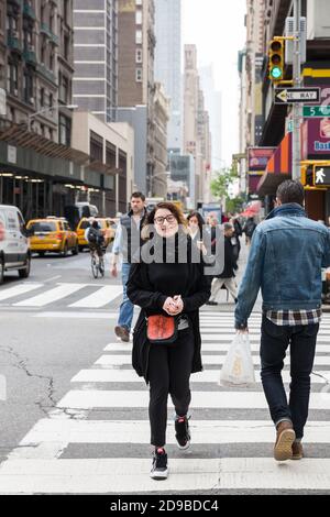 NEW YORK, USA - 02. Mai 2016: Kreuzung von 5th Av und W 31 St in NYC. Junge charmante Mädchen überquert die Straße an einem Fußgängerübergang. Manhattan stree Stockfoto