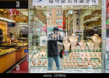 NEW YORK, USA - 28. Apr 2016: Manhattan Street scene. Ein junger männlicher Fotograf fotografiert ein Juweliergeschäft in Chinatown auf den Straßen von Manha Stockfoto