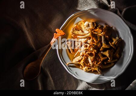 Frische, leuchtend orange Pfifferlinge in einem weißen Teller auf Leinen Tischdecke Stockfoto