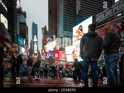 NEW YORK, USA - 30. Apr 2016: Times Square am Abend an einem regnerischen Tag. Massen von Amerikanern und Touristen auf dem Platz hell mit Billboa geschmückt Stockfoto