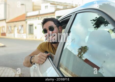 Bärtiger Mann Mit Sonnenbrille, Der Aus Dem Autofenster Schaut Stockfoto