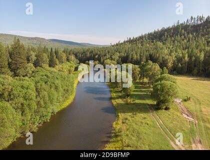 Drohne über einen Fluss, Landstraße und Wald. Luftaufnahme erstaunliche Blick auf Bäche, Nadelbäume und Hügel. Top Naturlandschaft an einem sonnigen Tag. Wasser Stockfoto