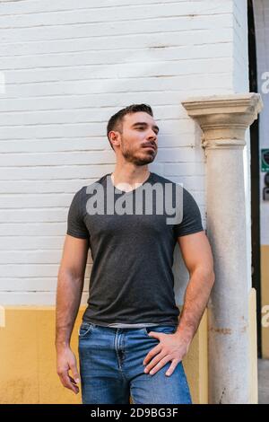 Weißer Mann lehnte sich im Herbst mit an eine Steinmauer Sonne auf seinem Gesicht Stockfoto
