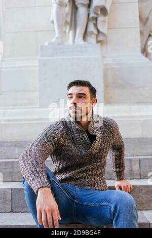 Weißer Mann in Herbstweste sitzt auf einem einzigen Platz Brunnen Stockfoto