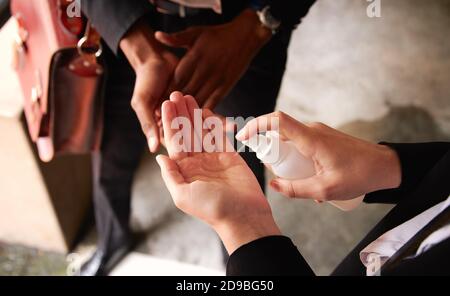 Nahaufnahme Von Geschäftsleuten, Die Während Der Gesundheitszeit Hände Mit Desinfektionsmittel Sprühen Pandemie Stockfoto
