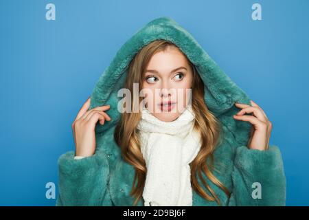 Stilvolle Frau in grünen Kunstpelz Mantel Blick weg isoliert Auf blau Stockfoto