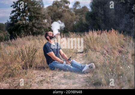 Stilvoller brutaler Raucher, der einen Vape genießt. Stilvoller Mann. Stockfoto