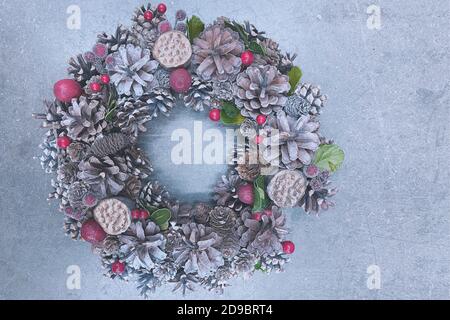 Weihnachtskranz aus Tannenzapfen auf betontem Hintergrund, horizontales Foto in kaltsilbernen Farben Stockfoto
