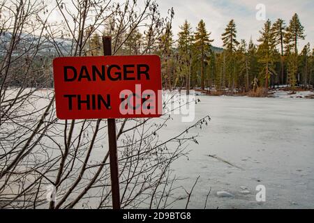 Dünnes Eisschild, das auf Gefahr/Gefahr auf gefrorenem Bergsee (Manzanita See im Lassen Volcanic National Park) hinweist. Stockfoto