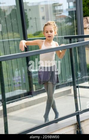 Ein Mädchen in einem Ballerina-Kleid tanzt auf einem heimischen Balkon. Stockfoto